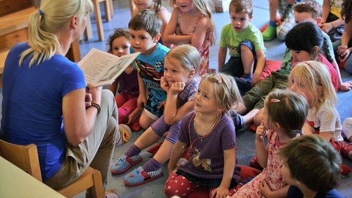 Erzieherin liest Kitakinder ein Buch vor