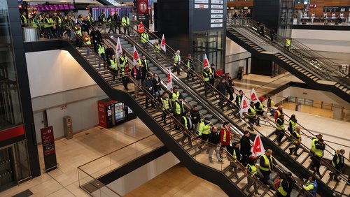Eine große Gruppe Streikender geht am Berliner Flughafen die Treppen runter.