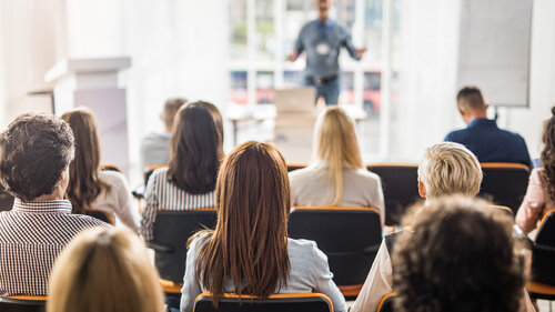 Back view of large group of business people having a training class in a board room.