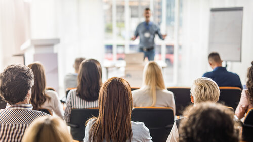 Back view of large group of business people having a training class in a board room.