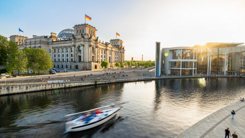 sailing boat passing the spree river in front of Reichstag in government district in Berlin at sunset