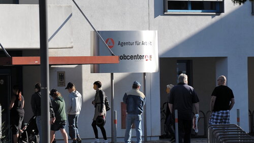 Arbeitssuchende stehen in einer Warteschlange vor der Bundesagentur für Arbeit