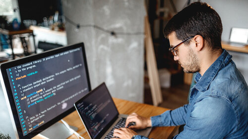 Männlicher Programmierer, der zu Hause in seinem Heimbüro arbeitet