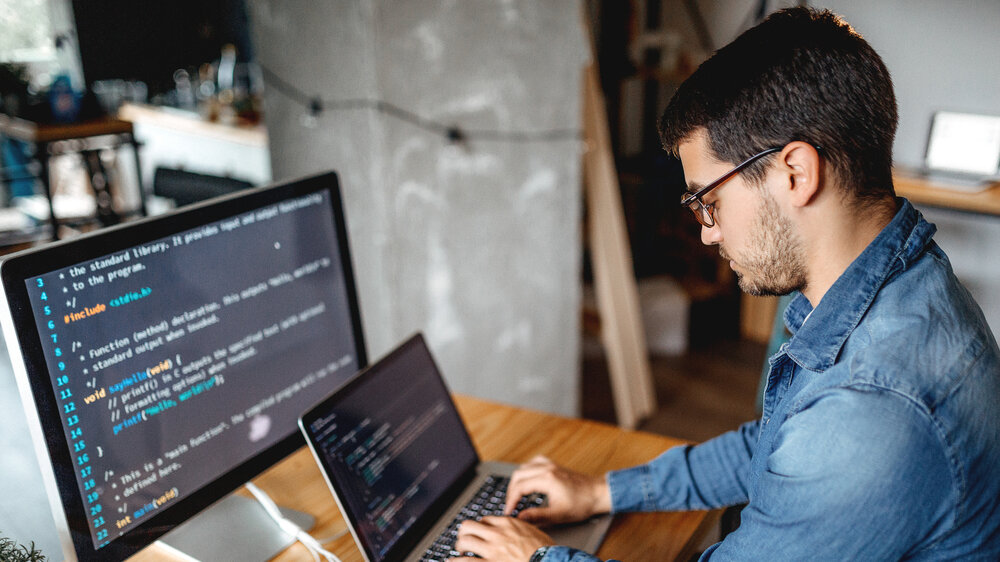 Männlicher Programmierer, der zu Hause in seinem Heimbüro arbeitet Männlicher Programmierer, der zu Hause in seinem Heimbüro arbeitet