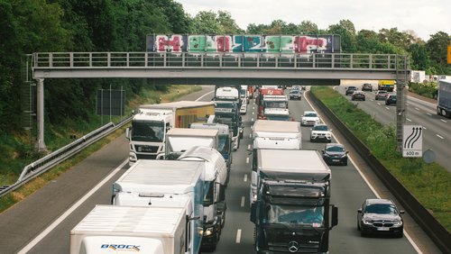 Eine lange Reihe von LKW steht auf der Autobahn im Stau und blockiert die linken beiden Spuren.