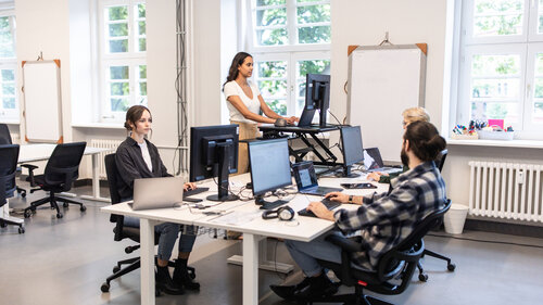 Gruppe von Fachleuten, die an ihren Schreibtischen in einem Großraumbüro arbeiten.