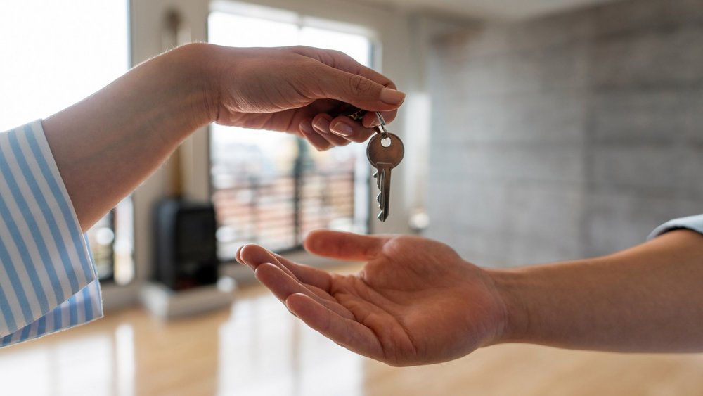 Nahaufnahme eines Immobilienmaklers, der einem Mann die Schlüssel seines neuen Hauses übergibt - Wohneigentumskonzepte