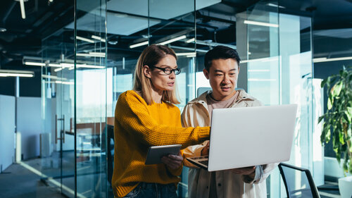 Business meeting of two employees, Asian and female colleagues, discussing the project, working in a modern office, looking at a laptop screen, discussing edits, and project success Business meeting of two employees, Asian and female colleagues, discussing the project, working in a modern office, looking at a laptop screen, discussing edits, and project success