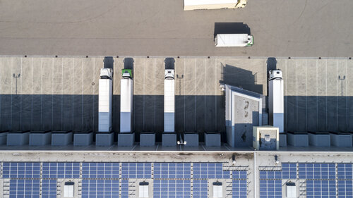 Fuhrpark vor einer Halle mit Solaranlagen