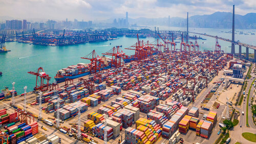 Aerial top view of container cargo ship in the export and import business and logistics international goods in urban city. Shipping to the harbor by crane in Victoria Harbour, Hong Kong.