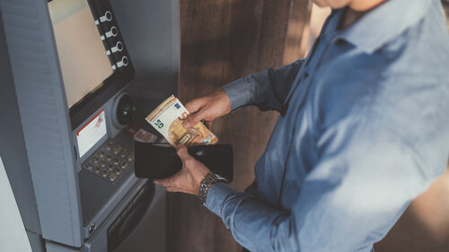 Businessman at the ATM withdrawing money, fifty euro banknotes
