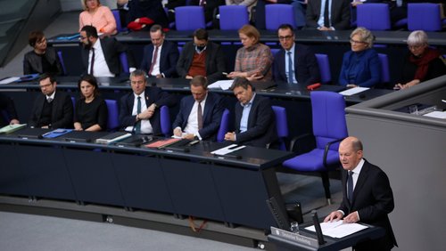 Olaf Scholz hält eine Rede im Deutschen Bundestag. Im Hintergrund sieht man die prall gefüllte Regierungsbank.