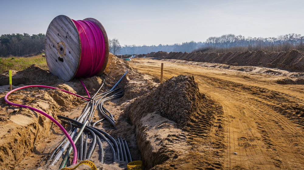 Kabel werden von einer Trommel im Boden auf einer Baustelle verlegt. Kabel werden von einer Trommel im Boden auf einer Baustelle verlegt.