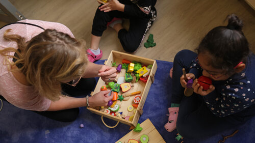 Eine Kindergärtnerin spielt mit zwei kleinen Kindern.