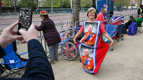 Frau mit Kröne trägt Kleid, auf dem Charles abgedruckt ist und posiert für die Kamera.