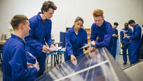 Eine Gruppe von jungen Ingenieuren begutachten Solarpanel. Unter ihnen ist nur eine Frau. 