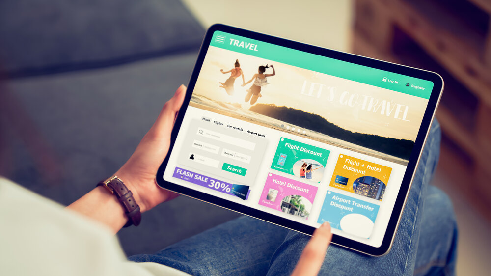 In Händen haltendes digitales Tablet mit Anwendung zur Buchung von Flug, Reise, Suche, Ticket Urlaub und Hotel auf Onlineplattformen. In Händen haltendes digitales Tablet mit Anwendung zur Buchung von Flug, Reise, Suche, Ticket Urlaub und Hotel auf Onlineplattformen.