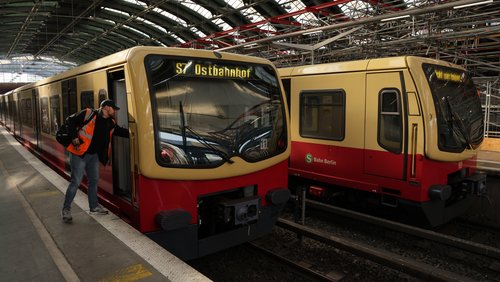 Stehende S-Bahnen in einem Bahnhof. Ein Mann in Warnweste verlässt die Fahrerkabine..