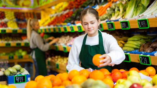 Fokussiertes junges Mädchen, das im Obst- und Gemüseladen der Familie arbeitet