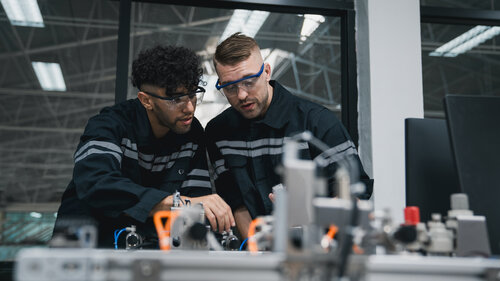 Student engineer Assembling Robotic Arm with computer in Technology Workshop. Service Engineer Holding Robot Controller and Checking Robotic Arm Welding Hardware. Student engineer Assembling Robotic Arm with computer in Technology Workshop. Service Engineer Holding Robot Controller and Checking Robotic Arm Welding Hardware.