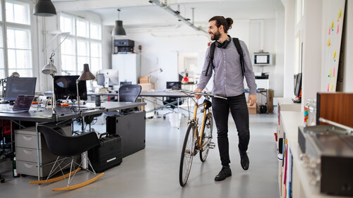 Businessman with a bicycle in office. Business professional going home after work.