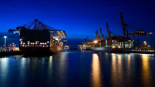 Zwei Schiffe werden nachts an einem Containerterminal entladen.